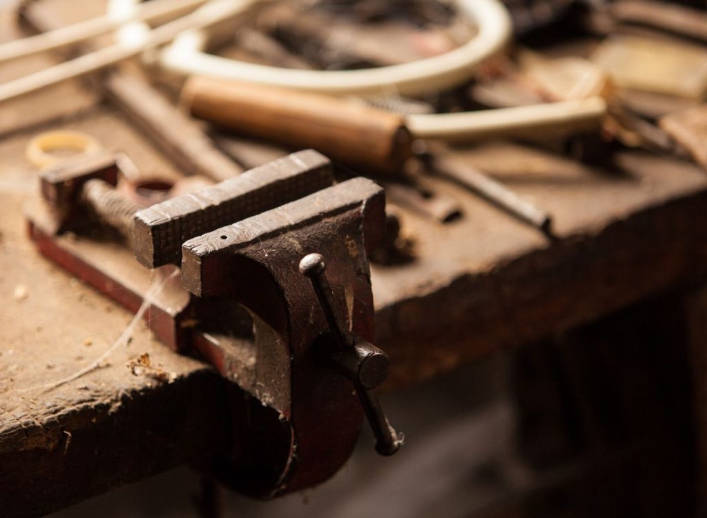 Établi d'atelier avec un vélo en cours de réparation et des outils anciens accrochés au mur